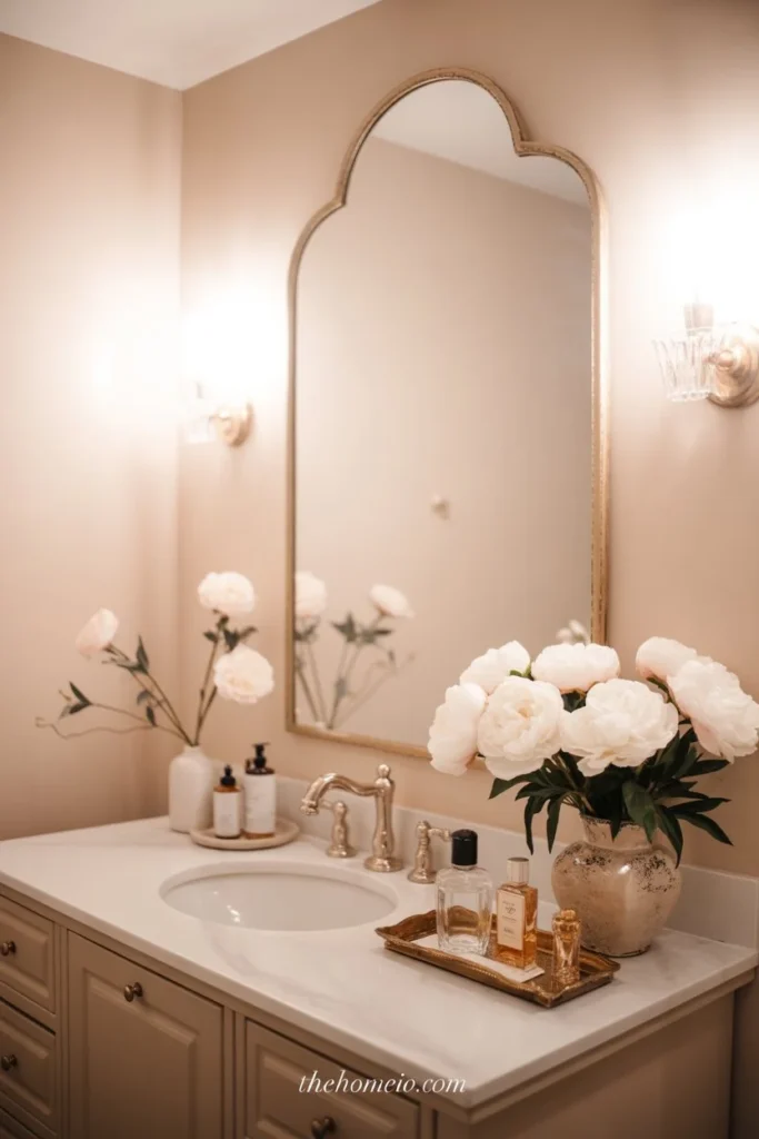 An elegant bathroom with a tall arched mirror, soft warm lighting, beige and white tones, beautiful vanity styling, and a calm luxurious mood.