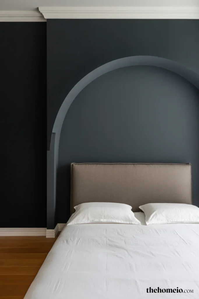 Black accent wall bedroom with painted arch detail framing upholstered headboard in lighter charcoal tone