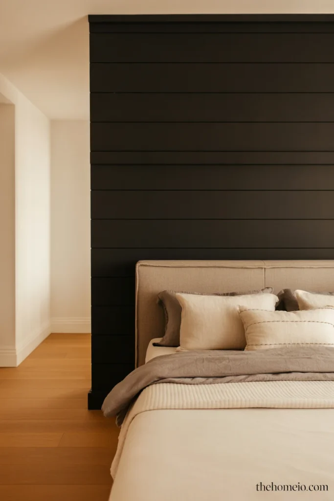 Black shiplap accent wall behind bed with linen headboard and layered neutral bedding in modern American bedroom