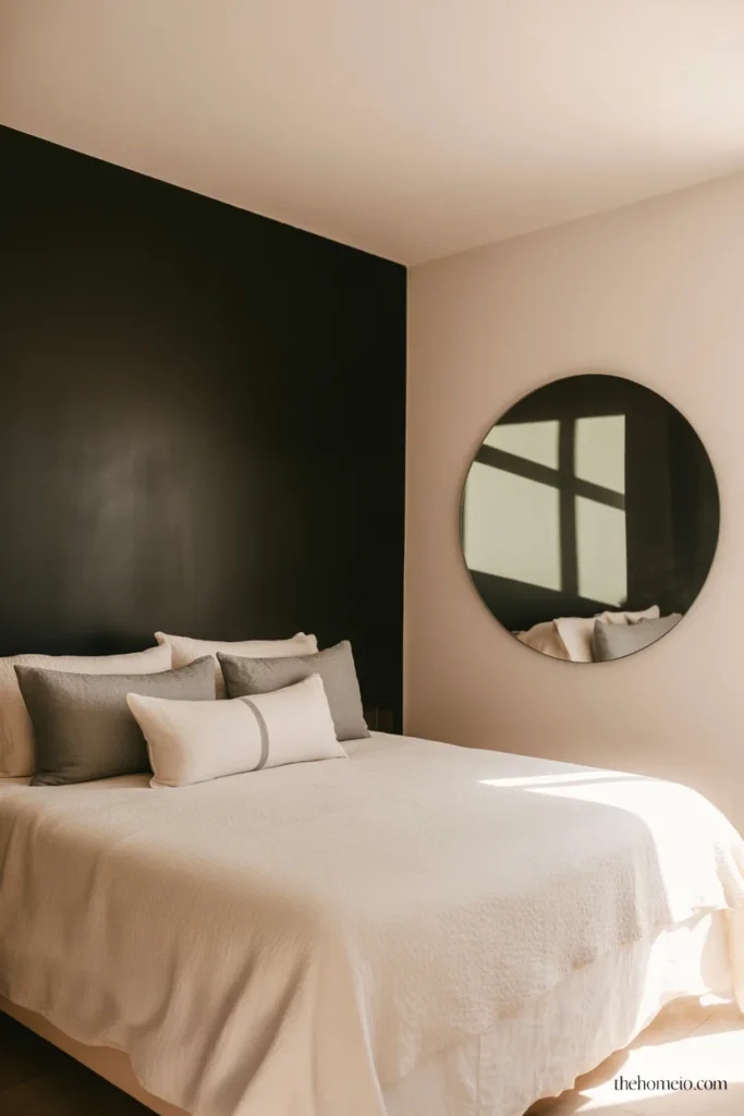 Small bedroom with single black accent wall behind bed white walls on three sides and large mirror reflecting light